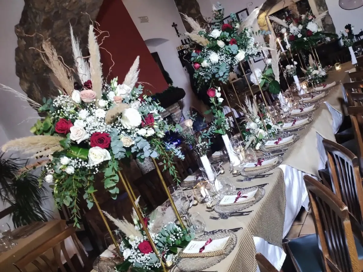 Tavolata allestita per un evento con composizioni di fiori