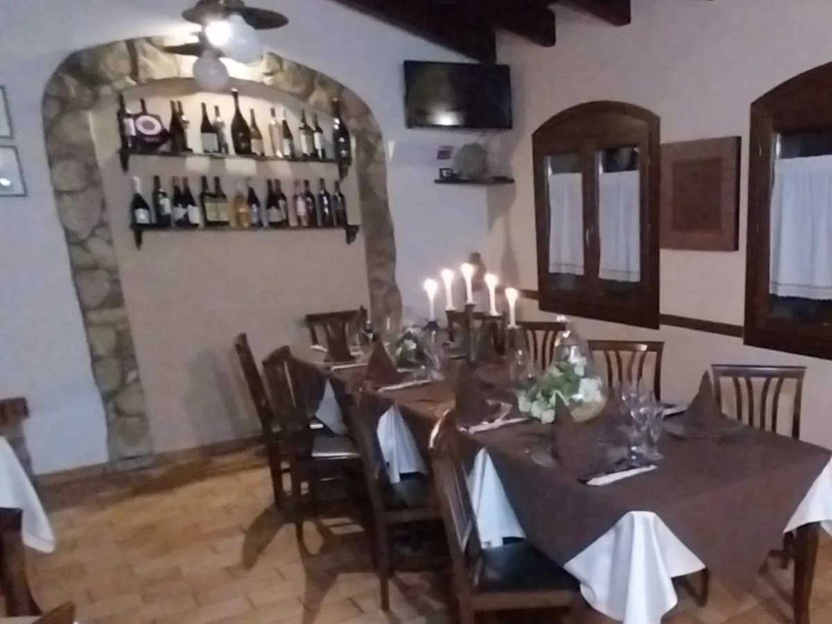 Angolo con arco in pietra, bottiglie di vino e tavolo con candele