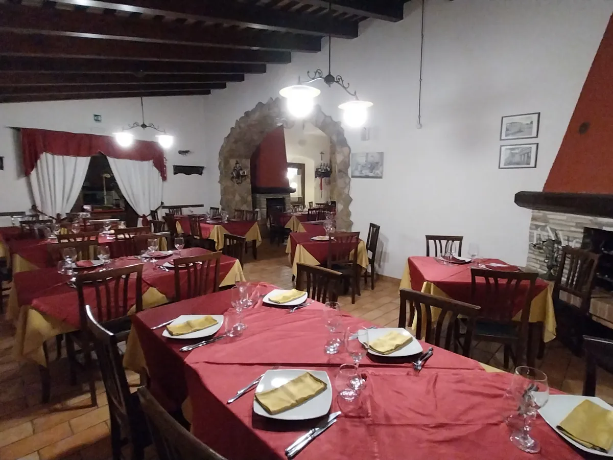 Sala del ristorante con camino in pietra e tavoli apparecchiati