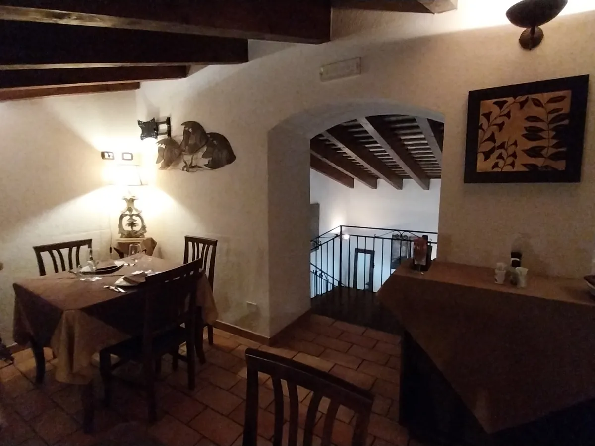 Sala sul soppalco con luci calde e tavoli apparecchiati