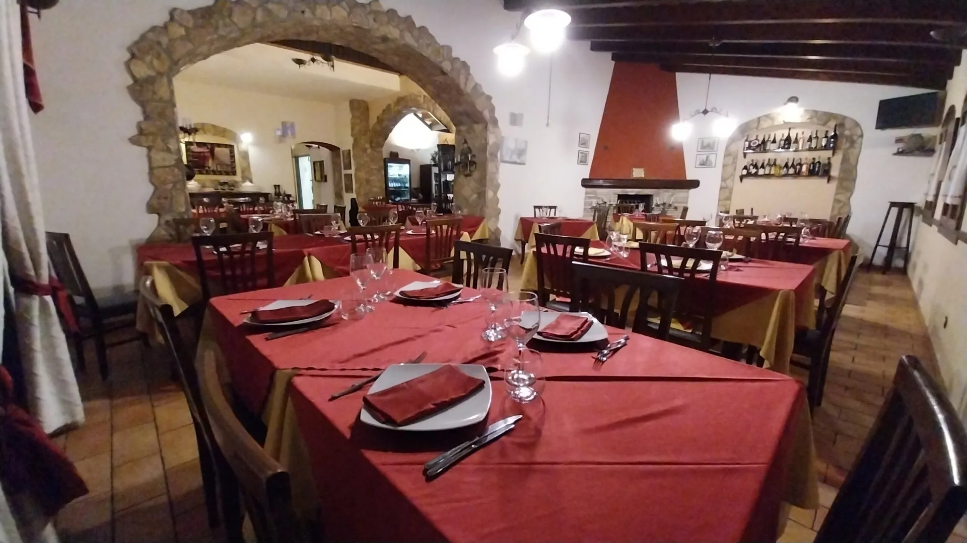 Sala principale de La Collinetta con arco in pietra, camino e tavoli apparecchiati