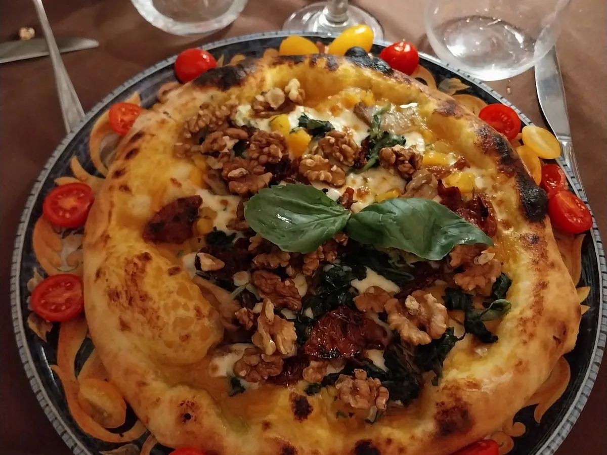 Pizza gastronomica con noci, basilico e pomodorini